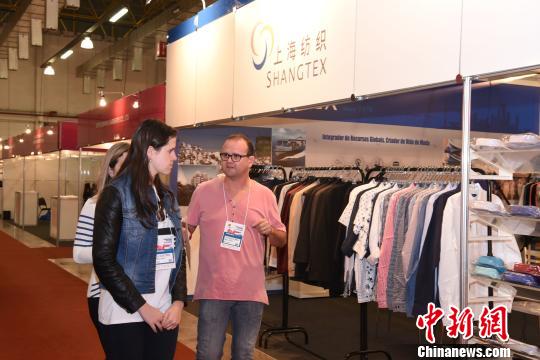 圖為外國客商在一家中國上海紡織企業(yè)展臺(tái)前走過?！∧尚邸z